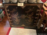 Front view of the black lacquer cabinet showing floral and bird motifs and metal hardware