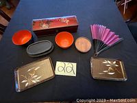 Full set of Asian wood items including two trays, decorative box, folding fan, stands, bowls, and coaster arranged on dark surface.