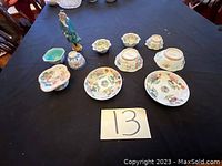 Various small Asian ceramic plates, bowls, and a standing figurine arranged on a table.