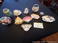 Overview image showing all porcelain items spread out on a black cloth including vases, plates, porcelain figurines, and basket container