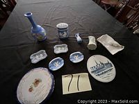 Full view of the lot items on a black cloth including plates, vases, jars, and small decorative pieces.