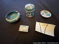 Full set of four Asian cloisonné items on black background: ashtray, lidded box, small plate, and matchbox holder with floral designs.