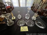 Overview of lot showing all glass items on table, clear glass decanters, candle holders, vase, and plates visible