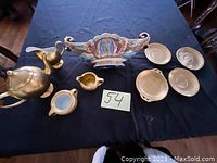 Photo of gold-colored tea set components and decorative painted vase