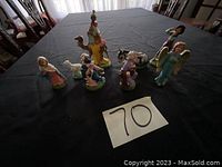 Overview photo showing all nativity set figurines laid out on a black surface including animals, wise men, Mary, Joseph, and angel.