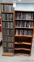Full view of two wooden CD shelves filled with CDs in jewel cases, one narrow and tall, one wider with additional empty shelves.