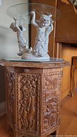 Full view of cherub centerpiece on carved wooden stand showing glass dish and resin figures.