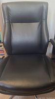 Front view of cushioned black leather-like desk chair backrest and seat