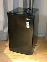 Closed front view of black Magic Chef bar fridge with power cord on top.