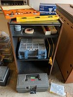 Photo showing orange box with Mastercraft rotary tool bits, box of PAR 20 LED flood bulbs, yellow spirit level, measuring tape, two plastic toolboxes, and repurposed wooden cabinet.
