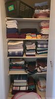 Shelving filled with neatly folded towels, sheets, blankets in various colors and patterns.