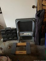 Milwaukee moving dolly with wooden padded platform, folded plastic PAC n Roll cart, and folding canvas chair in storage bag