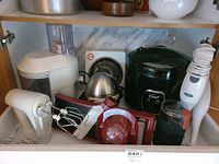 Wide angle photo showing all appliances and items included in the lot arranged in a cupboard space, showing condition and appearance.
