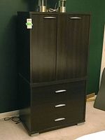 Front view of the dark wood wardrobe showing two doors on top and three drawers below, with silver handles.