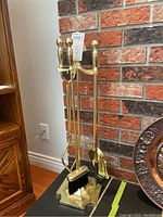 Full view of brass fireplace tool set including stand and four tools.