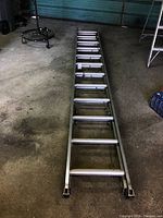 Full view of ladder extended on concrete garage floor with visible rungs and frame.