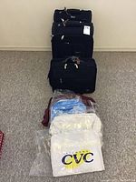 View showing all four black wheeled luggage pieces aligned vertically with five new bags placed in front.