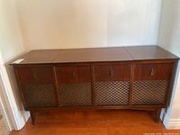 Front view of vintage wooden record player entertainment unit with woven speaker grills on four front panels.