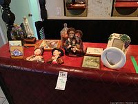 Photo of the lot items on a table including ceramic photo frames, religious statues, ceramic head plaques, glass jars and a ceramic vase.