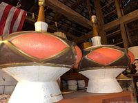 Close-up photo showing the ceramic base of the MCM lamp with textured white finish and oval coral pink and brown decorative element with gold trim detail.