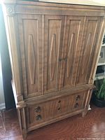 Front view of the vintage wooden armoire showing the four-panel doors and two drawers beneath with round wooden handles
