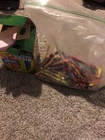 Plastic bag with multi-colored crayons next to an open box containing chalk sticks.
