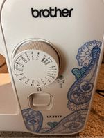 Close-up of Brother LX3817 sewing machine front showing stitch selection dial and decorative blue pattern.