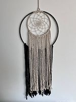 Large 14-inch dreamcatcher with black and white wrapped circular frame, beige web center, and long hanging tassels in beige and black yarns.
