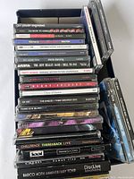 Photo of stacked miscellaneous CDs, mostly rock and alternative, cases showing titles and varying colors, highlighting the volume and type of music in the lot.