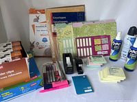 Photo showing majority of office supplies including paper reams, envelopes, folders, pens, tape dispensers, Post-it notes and sprays.