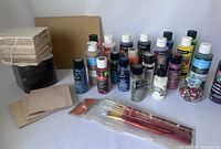 Full lot including wooden and plastic coasters, multiple acrylic paint bottles, brushes, and embellishments arranged on white backdrop