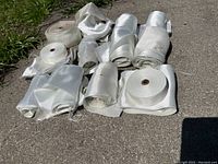 Photo showing 14 tightly and partially rolled fiberglass cloth rolls laid out on concrete.