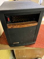 Front view of the black EdenPure quartz infrared heater showing power switch and wood-grain accent.