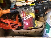 Remington orange electric chainsaw and Worx JawSaw high limb saw in cardboard box with high limb chainsaw kit in sealed packaging.