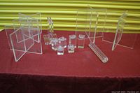 Wide view of various clear acrylic interlocking panels, blocks, and tealight holders arranged on a red table cover with a yellow roller door background.