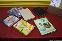 Books arranged on red cloth with yellow shutter background, displaying varied titles.