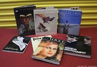 Seven fashion and photography themed books arranged on a red surface with yellow background.
