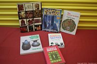Photo displaying six art-related books arranged on a red surface including 'Art Boxes', 'Sculpture in Plastics', and 'Man and His Symbols'.