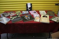 Photo showing all assorted books laid out on a red tablecloth with a yellow background. Various book covers visible, the lot label 'Book 1' is present.