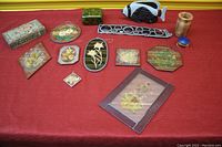 The full assortment of home decor items laid out on a red surface showing various decorative boxes, framed floral art pieces, a ceramic fish figurine, and wooden items.
