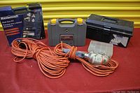 Full lot spread showing heat gun box, extension cord, trouble light, wrench case, toolbox, and screws box on red surface with yellow shutter background.