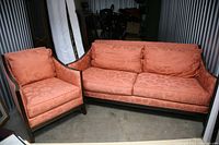Photo of salmon coloured three-seat couch and matching armchair set displayed together, showing fabric upholstery and wooden frame details.