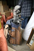 Golf bag filled with multiple golf clubs, showing the variety of club heads and grips, and external details of the bag.