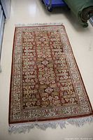 Full top-down view of red and ivory oriental rug laid flat on floor.