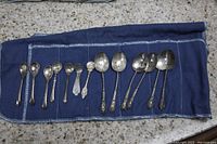 Image showing 11 assorted spoons laid out on blue cloth, varying in size and ornate design.