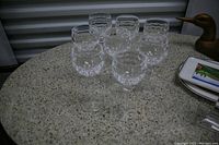Eight cut crystal goblets arranged on a round speckled tabletop