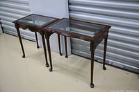 Two wood and glass nesting end tables, one with glass top and one missing glass top