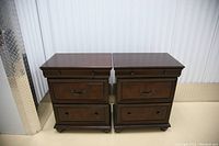 Front view of two identical dark brown wooden night stands side by side against a metal wall