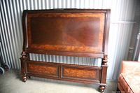 Wooden bed headboard panel with decorative inlaid wood grain and curved top edge, warm dark brown finish.