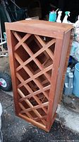 Front and angled view of cherry wood wine rack showing lattice compartments and surface wear